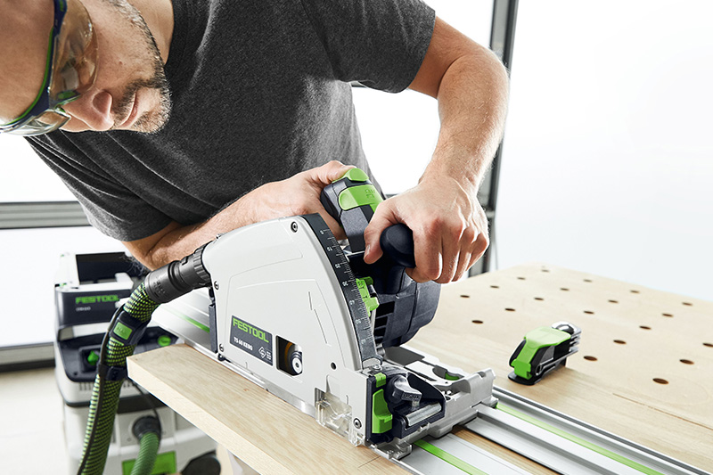 Man with a Festool circular saw cutting a board on a multifunction table