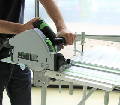 Slowly guide the portable circular saw at an even feed rate along the rail.