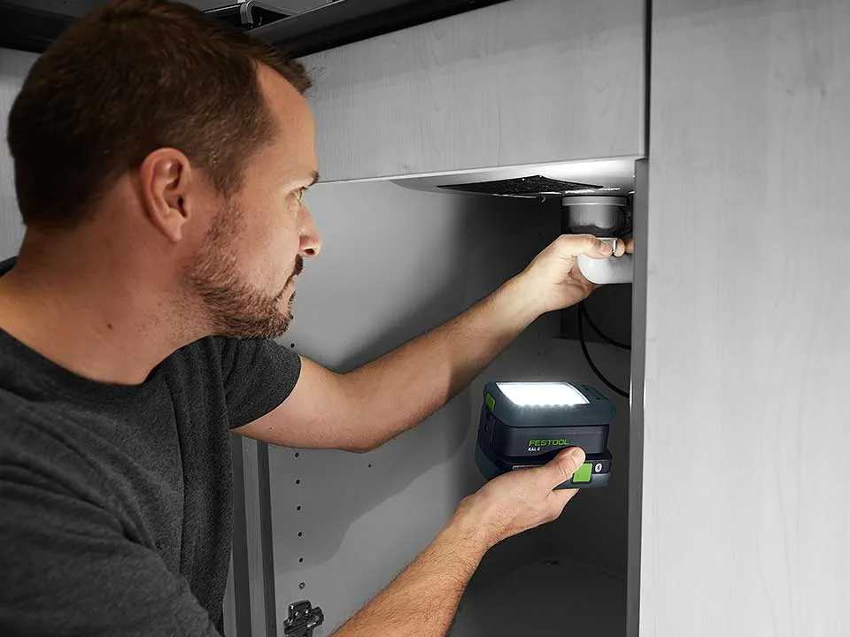 A man illuminates the connection of a washbasin with the SYSLITE KAL 2